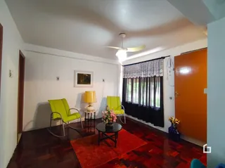 Sala de estar com piso de madeira escura e cortinas escuras.
