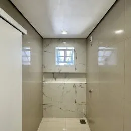 Banheiro com revestimento em mármore branco nas paredes.