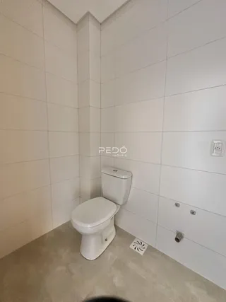 Foto de um banheiro com revestimento cerâmico branco e vaso sanitário.