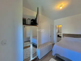 Quarto com cama e armário de espelho em ambiente claro.