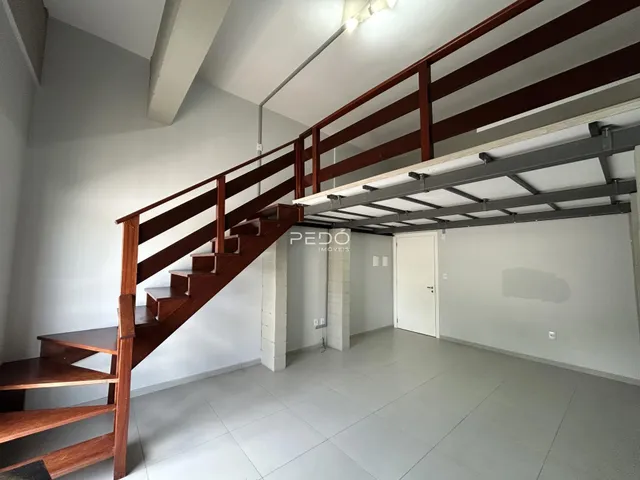 Ambiente interno com escadaria de madeira e piso claro.