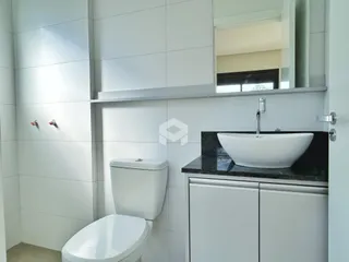 Banheiro moderno com revestimento branco e bancada escura.