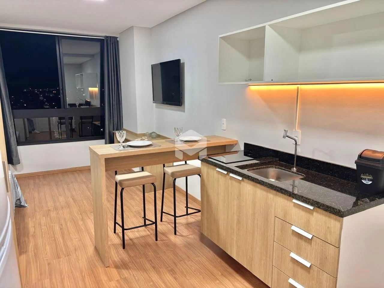 Interior de uma cozinha e sala de jantar com piso de madeira clara.