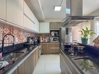 Cozinha moderna com armários e revestimentos coloridos.