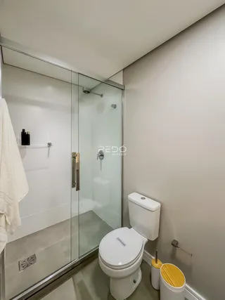 Um banheiro moderno com box de vidro e vaso sanitário branco.