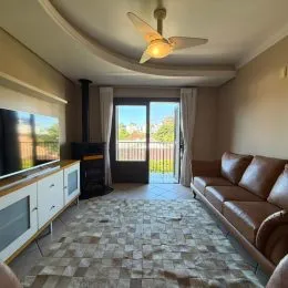 Sala de estar com porta de vidro que dá acesso ao exterior.