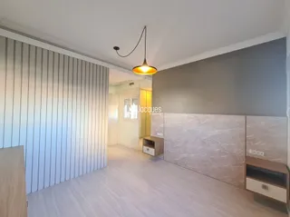Um corredor interno com piso de madeira clara e paredes brancas.