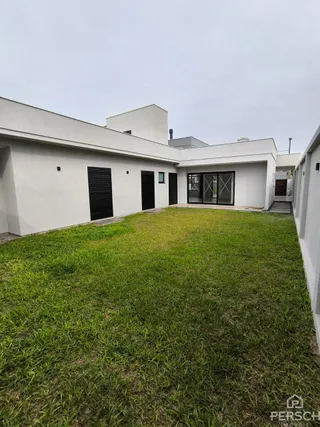 Fachada externa de uma casa moderna com gramado verde.