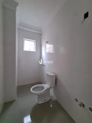Foto de um corredor interno com um vaso sanitário branco.