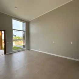 Foto de um cômodo interno com paredes claras e uma grande janela.