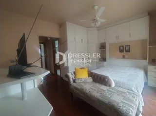 Quarto com cama e piso de madeira em uma residência.