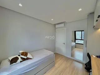 Quarto com cama e paredes cinzas.