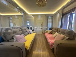 Sala de estar com sofás e piso de madeira em um apartamento.