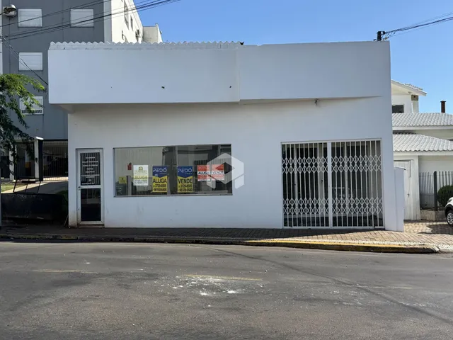 Fachada de uma casa branca com portão de ferro na rua.