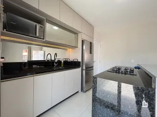 Foto de uma cozinha moderna com armários brancos e bancadas escuras.