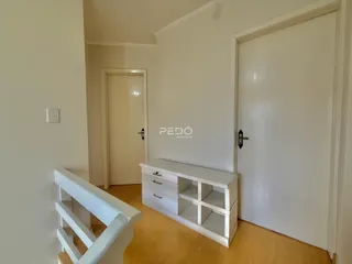 Hall de entrada com piso de madeira e portas brancas.