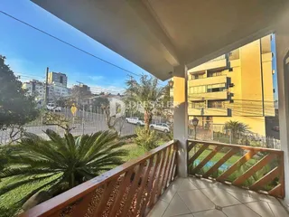 Vista da varanda com grade de madeira e paisagem verde.