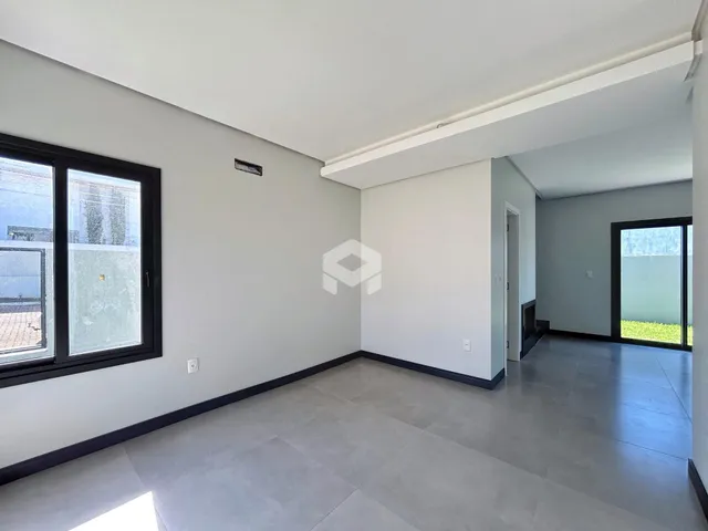 Interior de uma sala com paredes brancas e piso cinza.