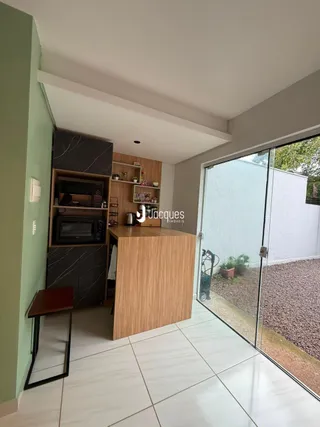 Interior de uma sala de estar com piso de cerâmica e porta de vidro para o exterior.