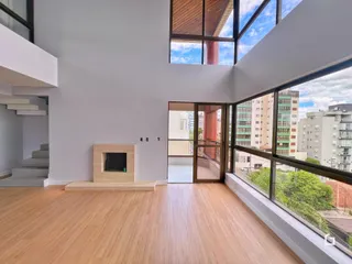 Sala de estar com piso de madeira e grandes janelas que oferecem vista da cidade.