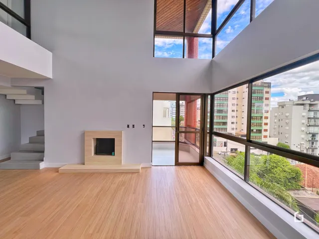 Sala de estar com piso de madeira e grandes janelas que oferecem vista da cidade.