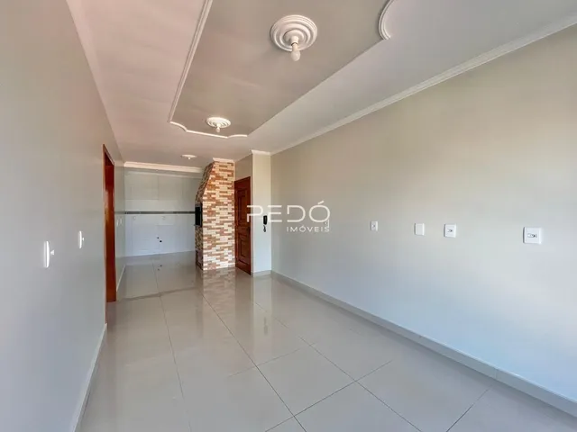 Corredor interno de uma residência com piso de cerâmica clara e paredes brancas.