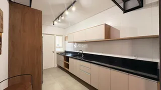 Foto de uma cozinha com armários brancos e bancada escura.