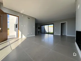 Sala de estar ampla com piso de cerâmica e porta de vidro que dá para o exterior.