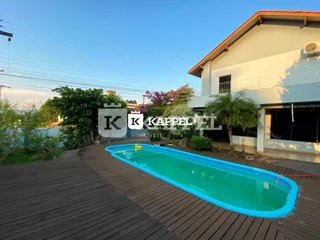 Piscina externa com deck de madeira em área de lazer.