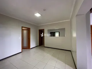 Hall de entrada com piso de cerâmica e portas de madeira.