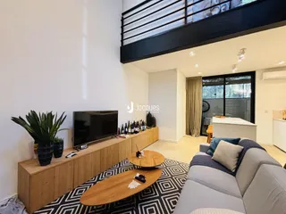 Sala de estar com sofá, televisão e móveis de madeira em um apartamento.