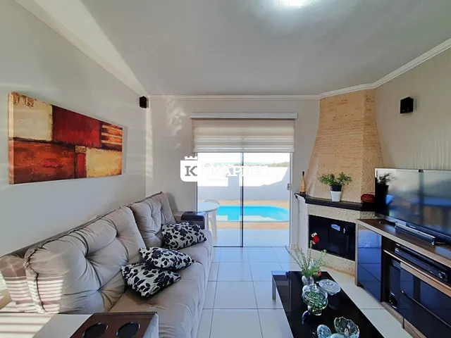 Sala de estar com sofá e lareira com vista para a piscina externa.