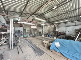 Espaço industrial com estrutura de metal e materiais armazenados.