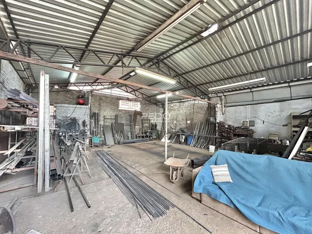 Espaço industrial com estrutura de metal e materiais armazenados.
