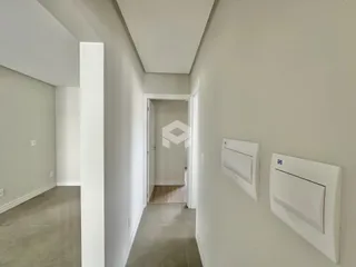 Corredor interno de uma residência com paredes brancas e piso claro.