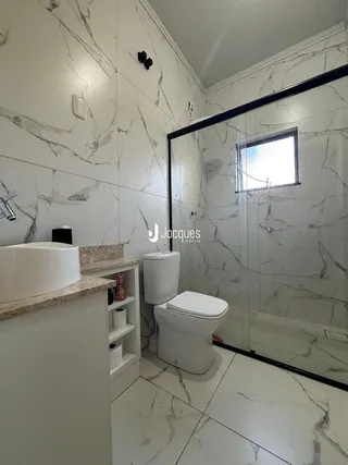 Banheiro moderno com revestimento em mármore nas paredes e piso.