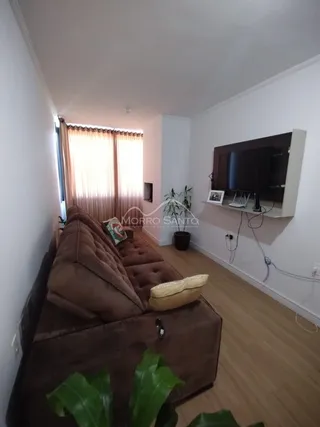 Sala de estar com um sofá grande e televisão montada na parede.