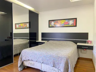 Quarto com cama grande e cabeceira escura em um ambiente bem iluminado.