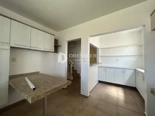 Interior de uma cozinha com armários brancos e piso de cerâmica.