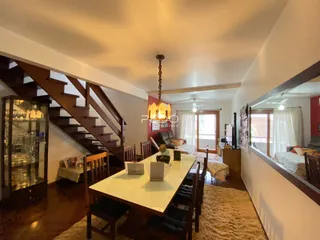 A sala de estar e jantar apresenta um piso de madeira e uma escadaria no interior da residência.