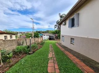 Vista externa de uma propriedade com jardim e muro de alvenaria.