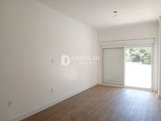 Uma sala com paredes brancas e piso de madeira clara.