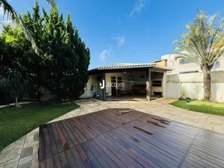 Vista externa de um quintal com deck de madeira e vegetação exuberante.