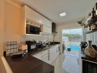 Vista da cozinha moderna com acesso a uma área externa com piscina.