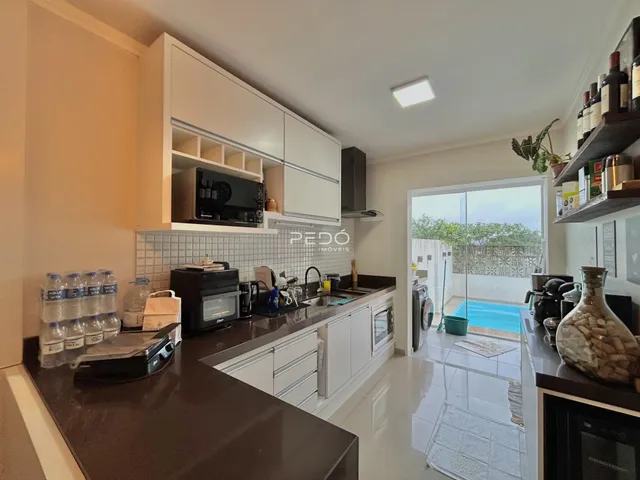 Vista da cozinha moderna com acesso a uma área externa com piscina.