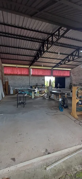 Imagem de um espaço interno com piso de concreto e estrutura metálica exposta.