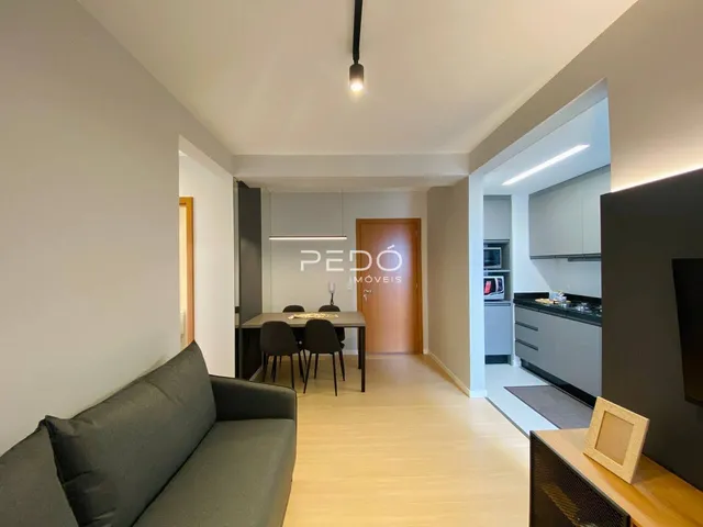 Ambiente interno de sala de estar e jantar com piso de madeira clara.