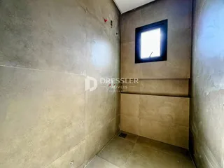Vista de um canto interno de uma sala com paredes em tom bege claro.