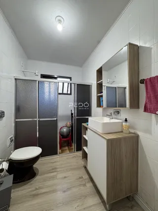Interior de um banheiro com piso de madeira e revestimento branco.