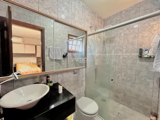 Foto de um banheiro com revestimento de cerâmica e box de vidro.